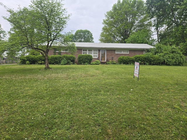 ranch-style house featuring a front lawn, brick siding, and metal roof