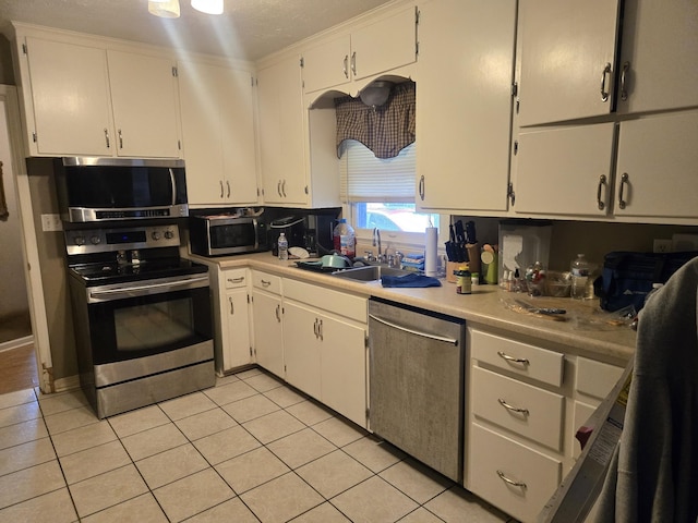 kitchen featuring light countertops, appliances with stainless steel finishes, light tile patterned floors, and a sink