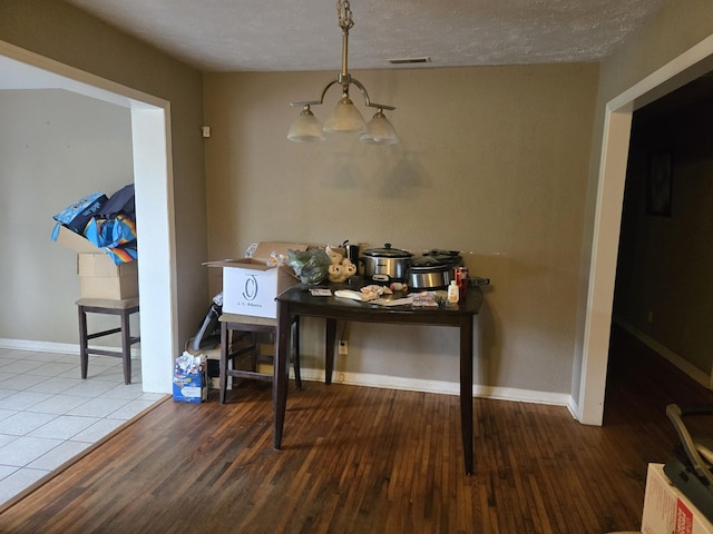 dining space featuring baseboards, wood finished floors, a textured ceiling, and visible vents