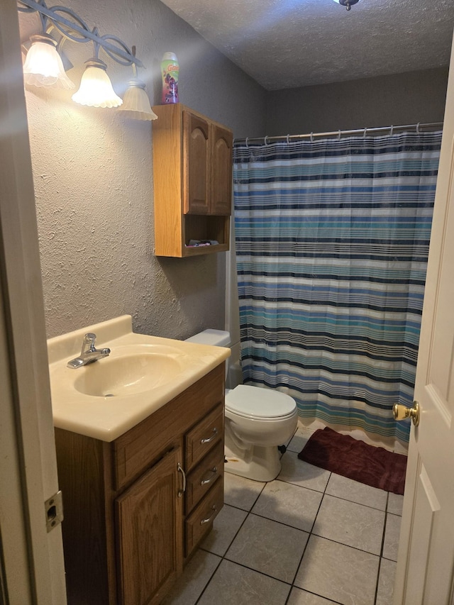 bathroom featuring a textured ceiling, toilet, tile patterned flooring, a textured wall, and vanity