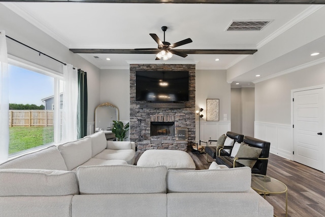 living room with ceiling fan, a fireplace, dark wood-style floors, visible vents, and crown molding