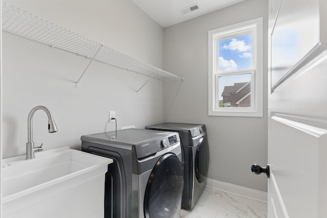 laundry area featuring a sink, laundry area, baseboards, washer and dryer, and marble finish floor