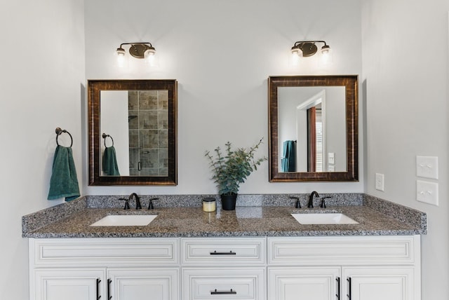 full bathroom with a tile shower, double vanity, and a sink