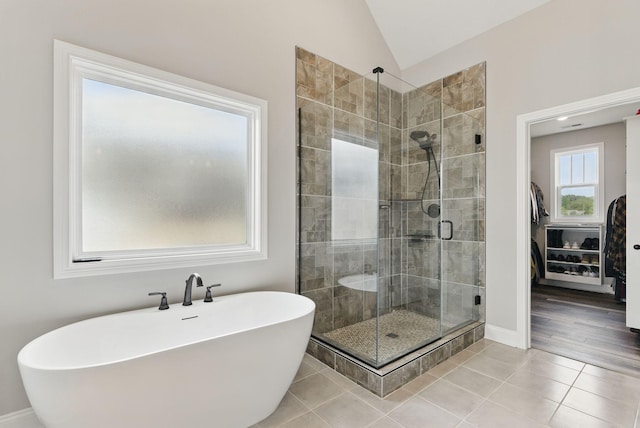 bathroom featuring lofted ceiling, a shower stall, a freestanding tub, baseboards, and tile patterned floors