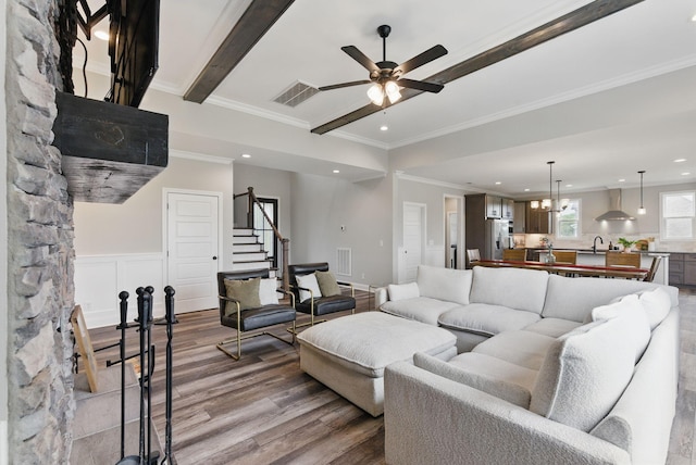 living area featuring visible vents, wood finished floors, a ceiling fan, and stairway