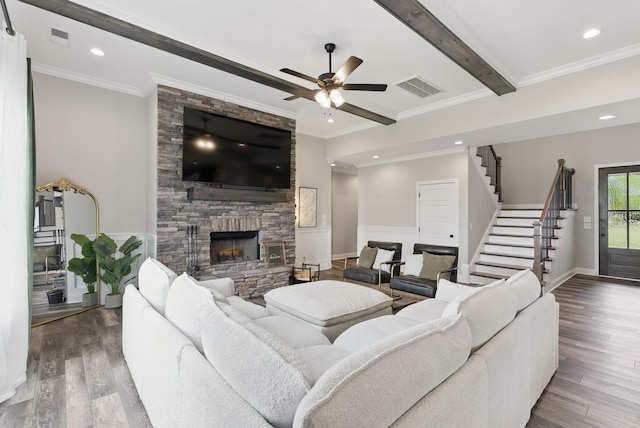 living room featuring wood finished floors, stairs, a stone fireplace, visible vents, and a ceiling fan