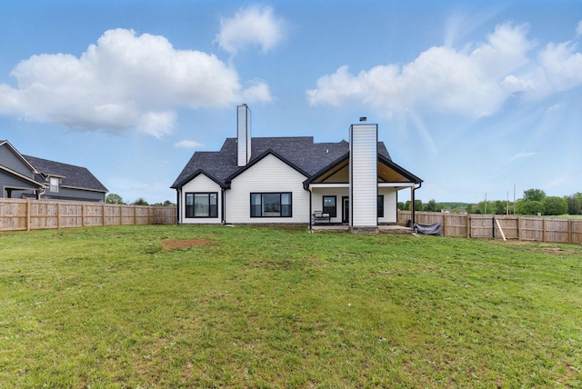 rear view of property with a chimney, a fenced backyard, and a lawn