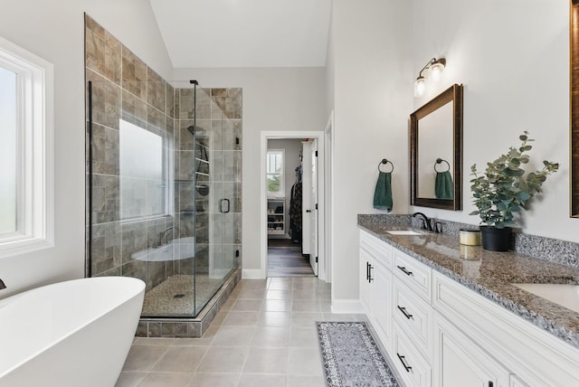 full bath featuring tile patterned floors, a stall shower, double vanity, a freestanding bath, and vaulted ceiling