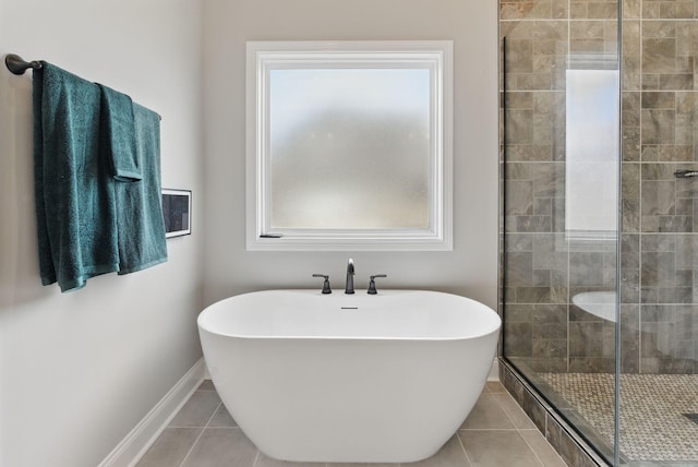 full bath with baseboards, a freestanding tub, a stall shower, and tile patterned flooring
