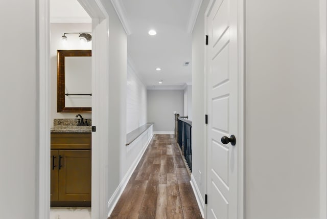 corridor with recessed lighting, ornamental molding, a sink, baseboards, and dark wood-type flooring