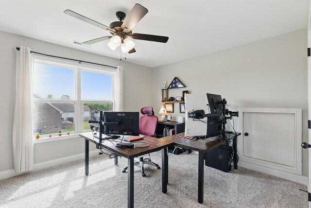 carpeted office space featuring visible vents, a ceiling fan, and baseboards