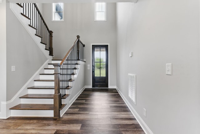 foyer with visible vents, stairway, wood finished floors, and baseboards