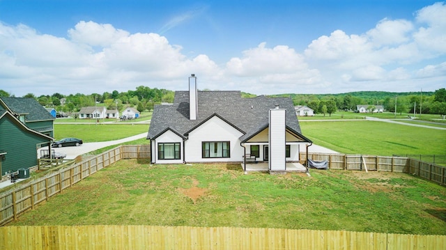 back of property with a lawn, a chimney, a fenced backyard, and a patio area