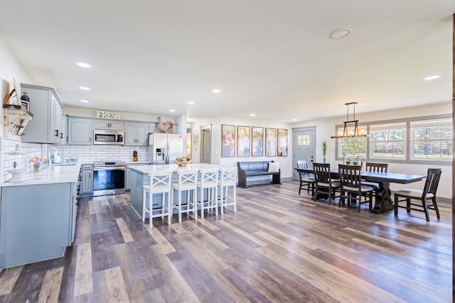 kitchen featuring dark wood-style floors, light countertops, a kitchen island, gray cabinetry, and appliances with stainless steel finishes