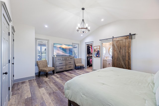 bedroom featuring a notable chandelier, a barn door, a sink, wood finished floors, and vaulted ceiling