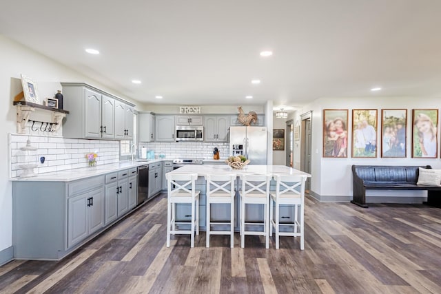 kitchen with light countertops, gray cabinetry, dark wood finished floors, and stainless steel appliances