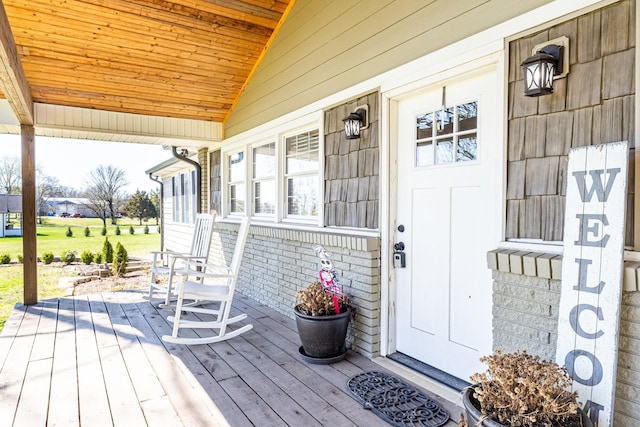 view of exterior entry featuring brick siding and covered porch