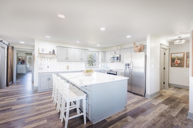 kitchen with a center island, open shelves, a barn door, light wood-type flooring, and stainless steel appliances