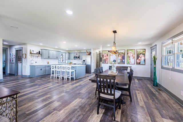dining area with dark wood-style flooring, baseboards, an inviting chandelier, and recessed lighting