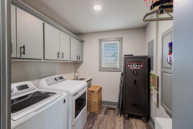 washroom featuring baseboards, independent washer and dryer, cabinet space, a sink, and wood finished floors