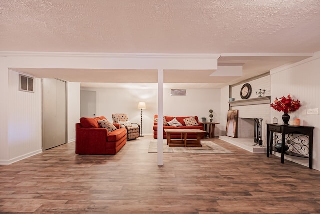 living room featuring a textured ceiling, wood finished floors, a fireplace, and visible vents