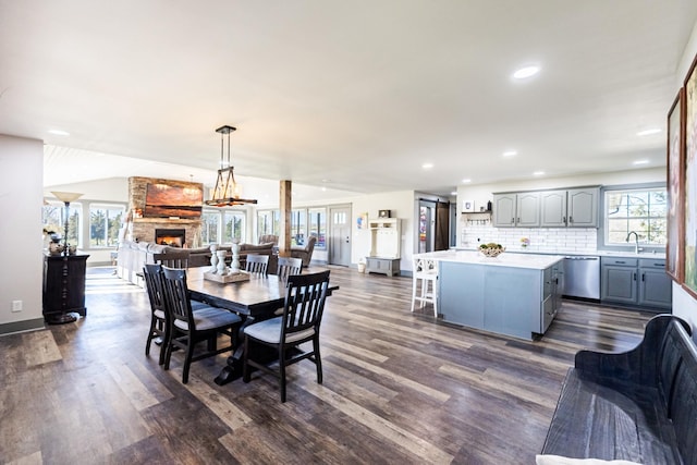 dining room with a fireplace, dark wood-type flooring, recessed lighting, lofted ceiling, and baseboards