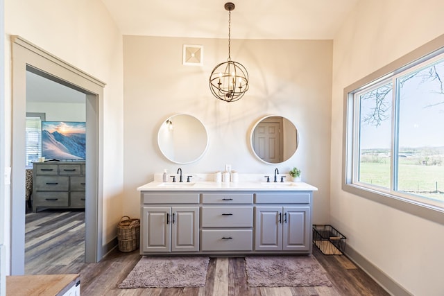 bathroom with a chandelier, double vanity, a sink, and wood finished floors