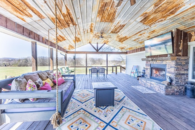deck with ceiling fan and an outdoor stone fireplace