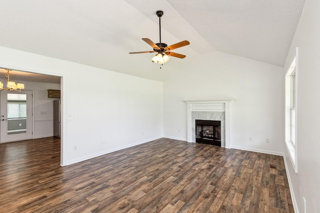 unfurnished living room featuring baseboards, a high end fireplace, dark wood-style floors, ceiling fan with notable chandelier, and lofted ceiling