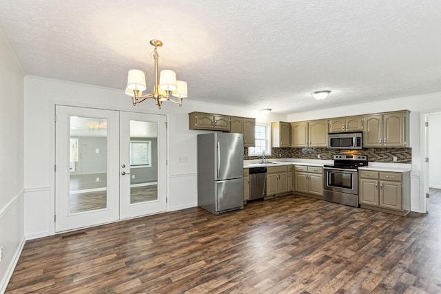kitchen featuring tasteful backsplash, dark wood-style flooring, light countertops, appliances with stainless steel finishes, and a chandelier