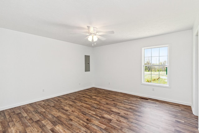 spare room featuring dark wood-style flooring, ceiling fan, electric panel, and baseboards