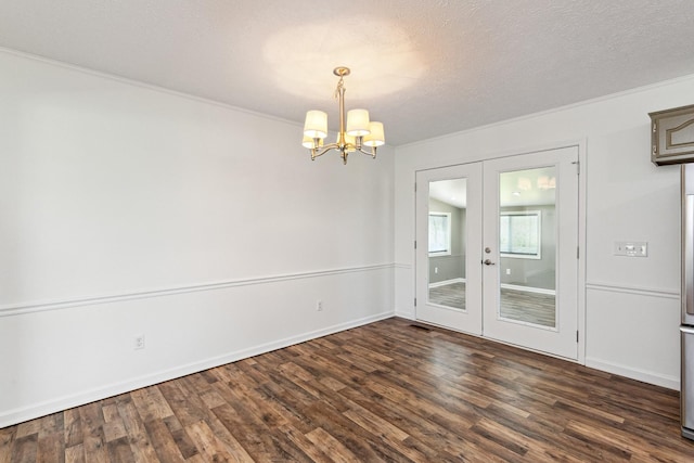 unfurnished dining area featuring an inviting chandelier, dark wood-style flooring, a textured ceiling, crown molding, and french doors
