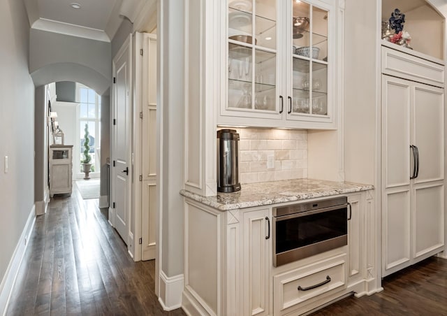 700 Pendragon Ct, Franklin, TN 37067 - bar with dark wood-type flooring, arched walkways, baseboards, and backsplash