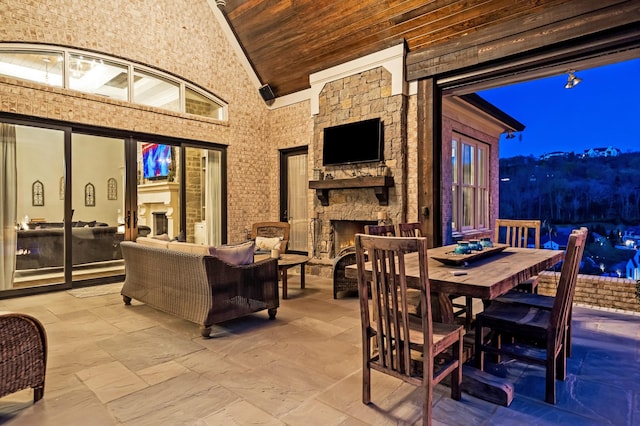 700 Pendragon Ct, Franklin, TN 37067 - dining area featuring high vaulted ceiling, stone tile floors, an outdoor stone fireplace, and wood ceiling