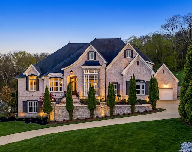 700 Pendragon Ct, Franklin, TN 37067 - french country home with concrete driveway, a garage, a front lawn, and brick siding