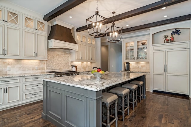 700 Pendragon Ct, Franklin, TN 37067 - kitchen with custom range hood, dark wood-style flooring, a chandelier, an island with sink, and beamed ceiling