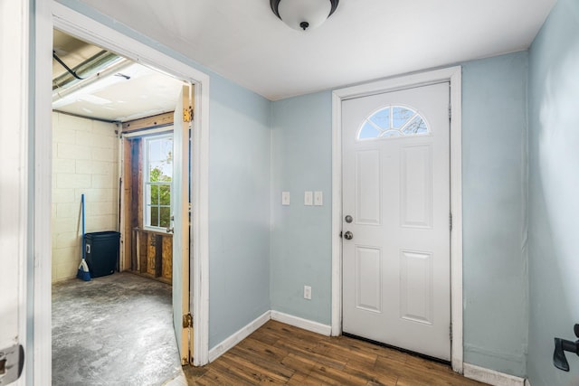 entrance foyer featuring healthy amount of natural light, dark wood-type flooring, baseboards, and concrete block wall