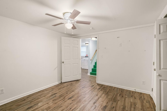 empty room with washer / clothes dryer, wood finished floors, baseboards, and ceiling fan