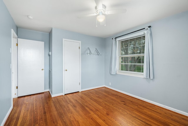 unfurnished bedroom featuring baseboards, wood finished floors, and a ceiling fan