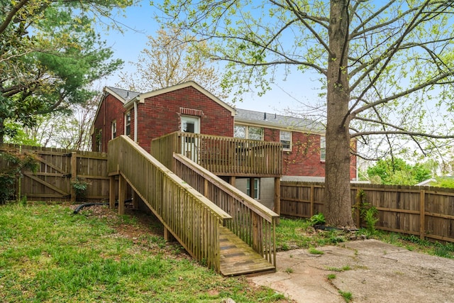 rear view of property with brick siding, a fenced backyard, a deck, stairway, and a gate