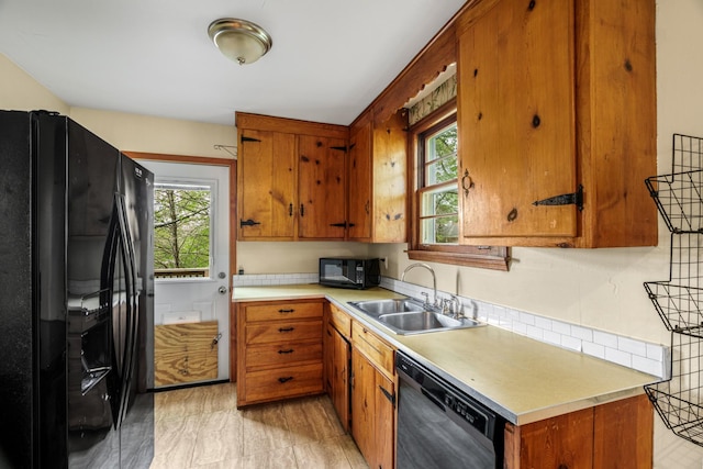 kitchen featuring black appliances, a sink, plenty of natural light, and light countertops