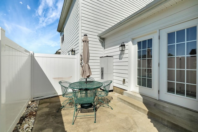 view of patio with outdoor dining space, entry steps, french doors, and fence