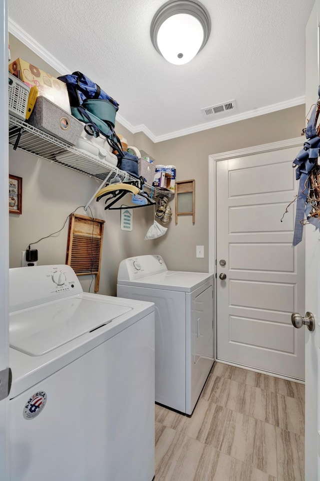 clothes washing area featuring visible vents, laundry area, a textured ceiling, crown molding, and washing machine and clothes dryer