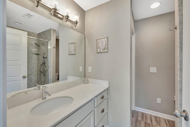 bathroom with vanity, baseboards, a stall shower, toilet, and visible vents
