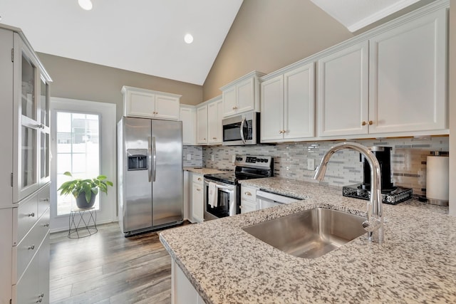 kitchen with appliances with stainless steel finishes, a sink, white cabinetry, and light stone counters