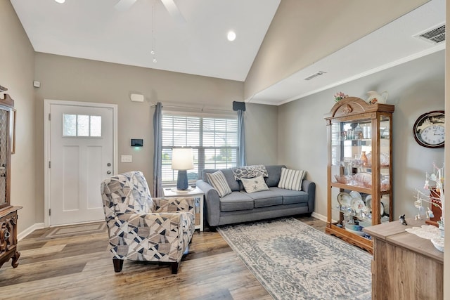 living room featuring light wood-type flooring, vaulted ceiling, and visible vents
