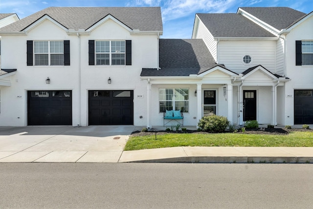view of property featuring an attached garage, a shingled roof, and driveway