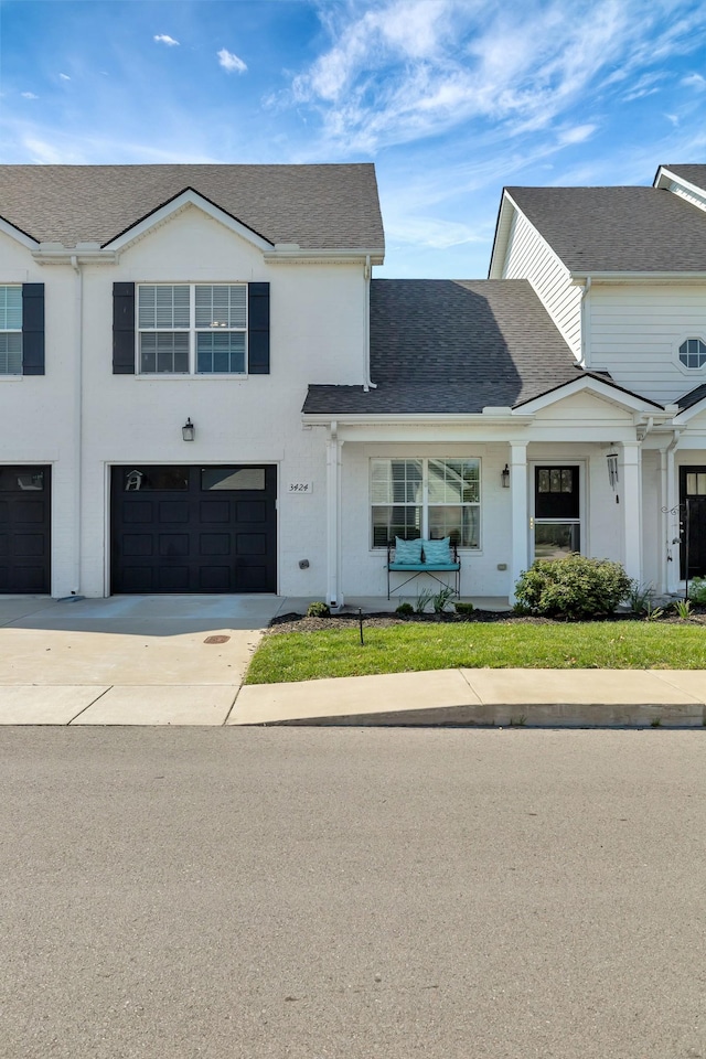 view of property featuring roof with shingles, driveway, stucco siding, and an attached garage