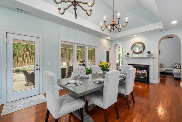 dining space featuring arched walkways, visible vents, hardwood / wood-style flooring, and an inviting chandelier