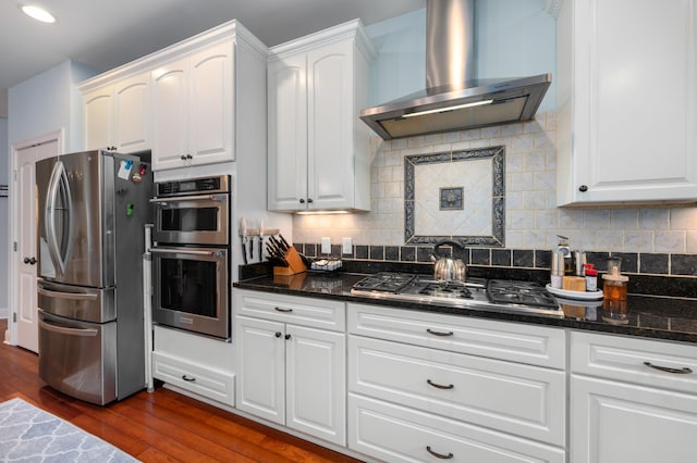 kitchen featuring tasteful backsplash, dark wood finished floors, wall chimney exhaust hood, and stainless steel appliances
